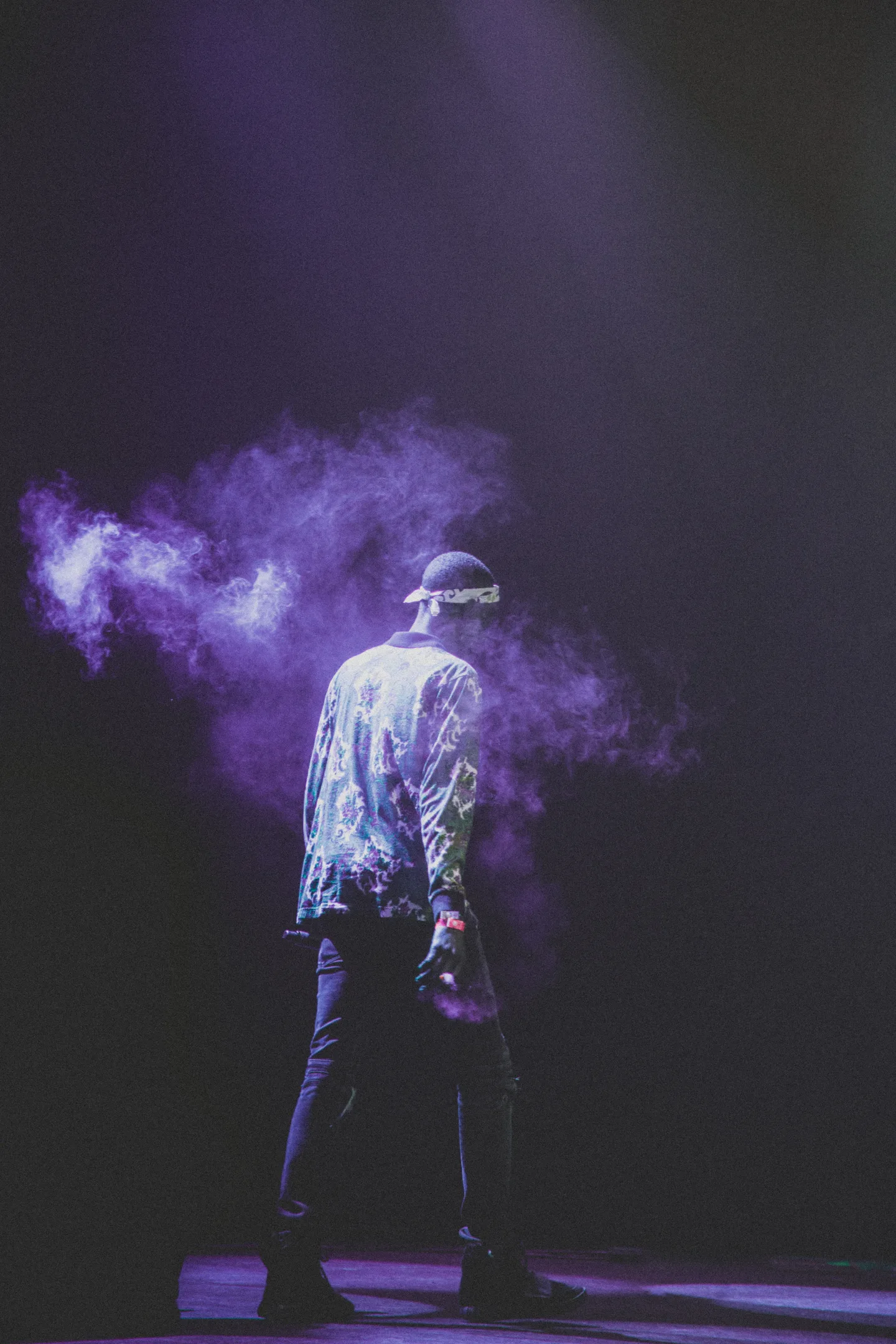 A performer surrounded by purple stage smoke